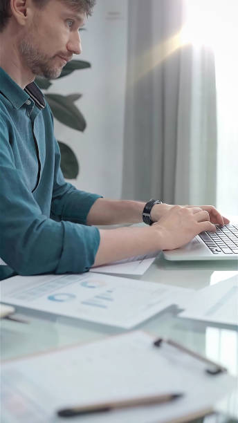 istock Entrepreneur wearing green shirt is working at laptop with data analysis charts. Vertical business portrait. Business people concept 2169490491
