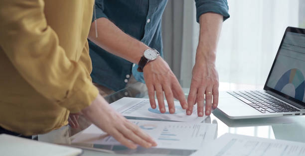 istock Business people, professionals analyzing financial charts and data on a desk while standing and using laptop computer in office 2169491309