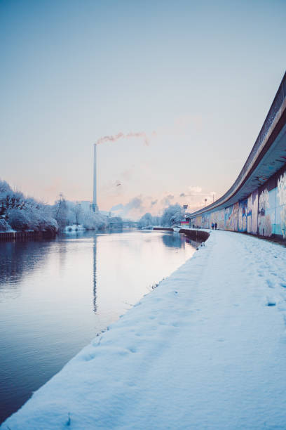 Winter City Landscape with a Snow Covered Walking Path Near a Calm River