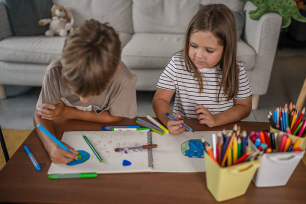 istock Two children interacting with a globe and drawing the planet at home - idea of securing a healthy, positive future for people and the planet 2169501590