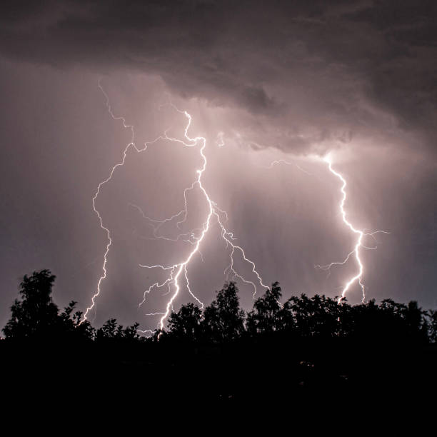 beautiful lightning during a thunderstorm at night in a forest that caused a fire, against a dark sky with rain