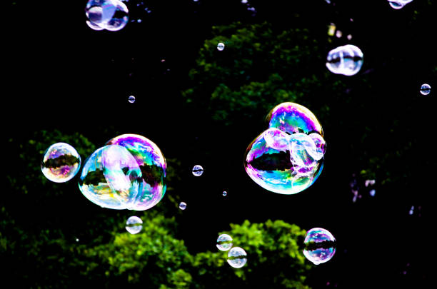 Soap Bubble in the air with dark background, water enclosing air that forms a hollow sphere with an iridescent surface.