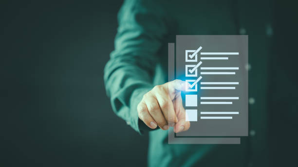 istock Manager present an office document, emphasizing the auditing concept of business performance. He engages in filling out a digital form checklist, conducting assessment and evaluation for online exam. 2169508836