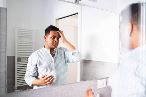 Man looking at reflection in bathroom mirror and fixing his hair