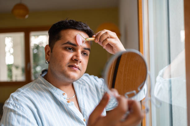 Man using jade roller for facial care in front of mirror