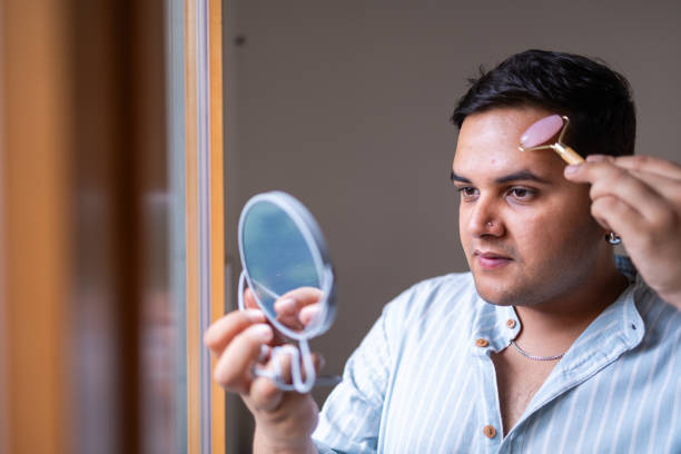 istock Man using jade roller for skincare in front of a mirror 2169519521