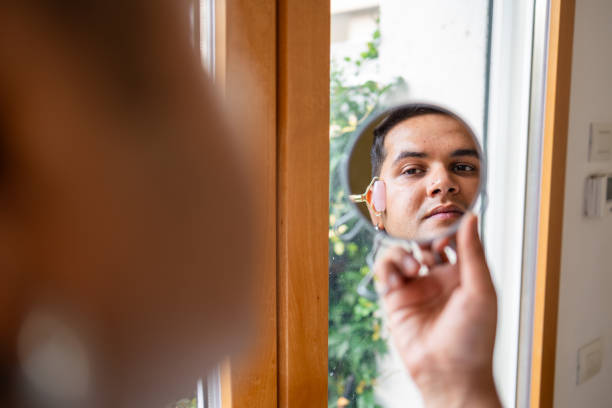 istock Man using a handheld mirror to examine his face closely 2169519523