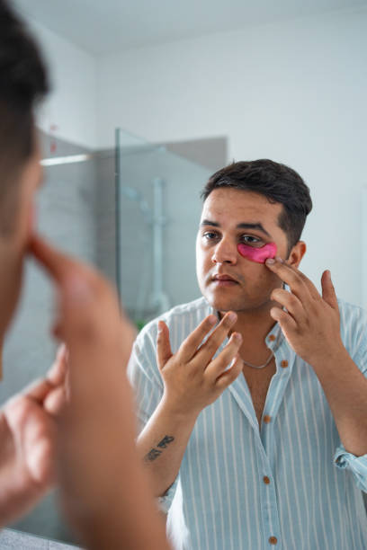 istock Man applying skincare patch while looking in bathroom mirror 2169519524