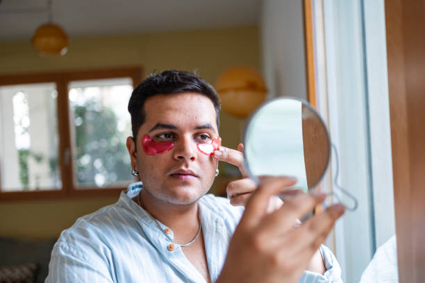 istock Man applying under eye patches while looking in the mirror 2169519529
