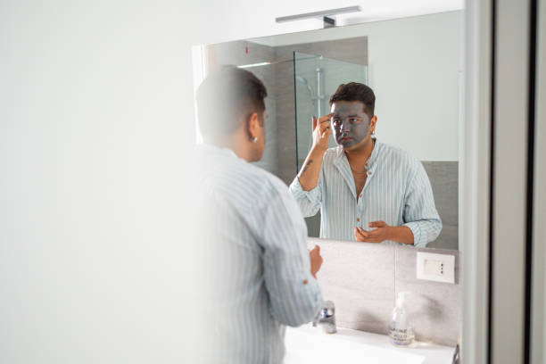 istock Man applying face mask in modern bathroom at home 2169519538