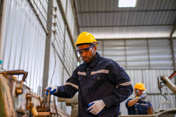 istock Blue collar workers at machine shop with welding robot arm. 2169536323