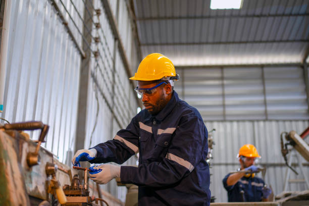 istock Blue collar workers at machine shop with welding robot arm. 2169536324