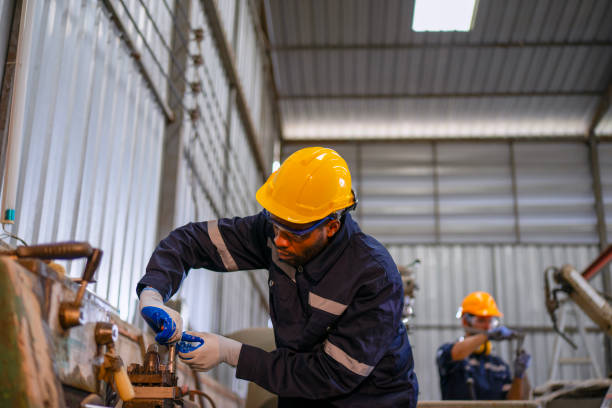 istock Blue collar workers at machine shop with welding robot arm. 2169536325