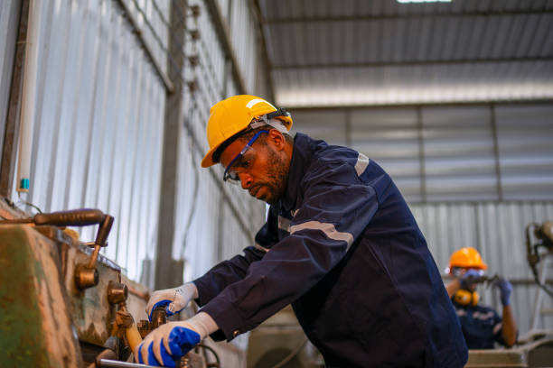 istock Blue collar workers at machine shop with welding robot arm. 2169536326