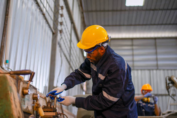 istock Blue collar workers at machine shop with welding robot arm. 2169536327