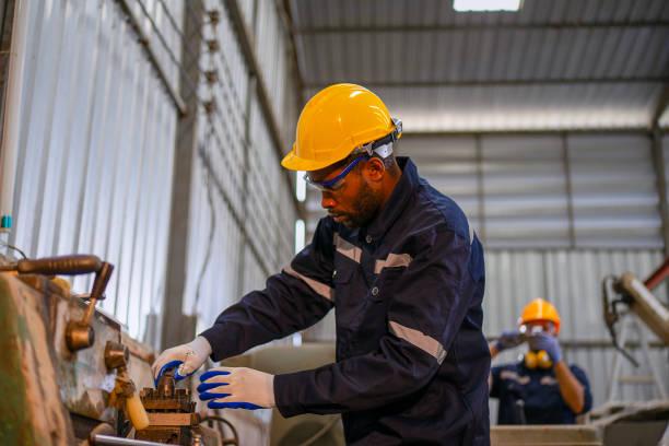 istock Blue collar workers at machine shop with welding robot arm. 2169536373