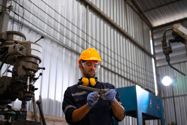istock Blue collar workers at machine shop with welding robot arm. 2169536374