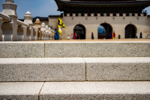 A low-angle view of granite steps leading up to the entrance of a historic palace, with traditional architecture visible in the background. The image highlights cultural heritage and meticulous craftsmanship. Perfect for themes of history, architecture, and cultural exploration.