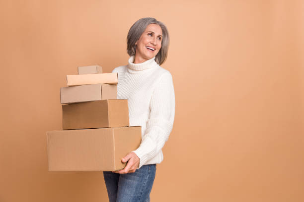 istock Photo of funky dreamy woman wear knitted pullover holding boxes stack looking empty space isolated beige color background 2169548406
