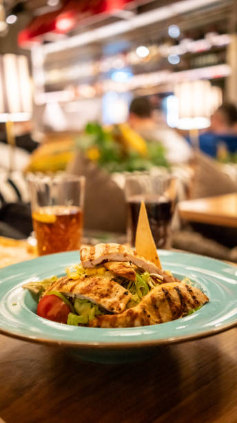 salad with chicken is in dish on table foreground focus on foreground cafe is background vertical food still stock photo