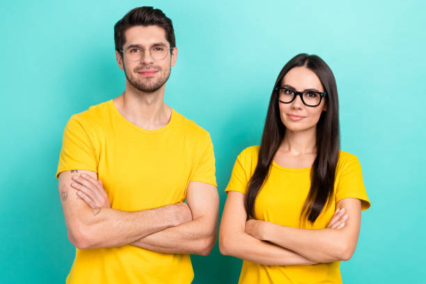 istock Photo of two programmers young couple working office senior developers wear same yellow t-shirt crossed arms isolated on aquamarine color background 2169549806
