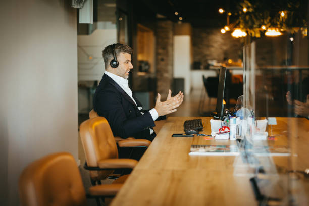 istock Businessman wearing headset talking at computer 2169550881