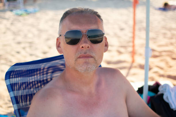 handsome middle-aged man with sitting on a chair on the beach enjoying