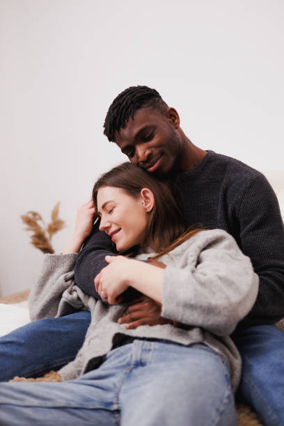 istock Smiling and relaxed multiethnic couple hugging on bed at home 2169558601