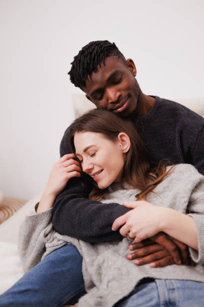 istock Relaxed multiethnic couple in sweaters sitting on bed at home 2169558621