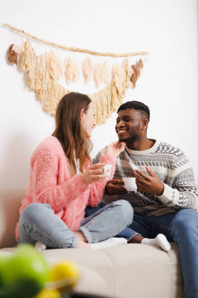 istock Multiethnic romantic couple with coffee relaxing on couch at home 2169559067
