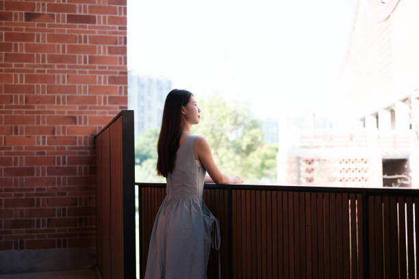 Young woman leaning on balcony railing and thinking