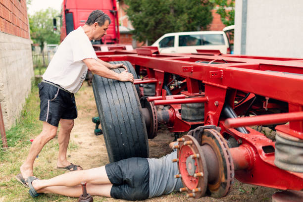 The men are replacing the tires on the semi truck trailer.