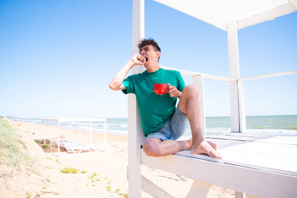 istock A young attractive man drinks coffee, relaxes and works by the sea. 2169563720