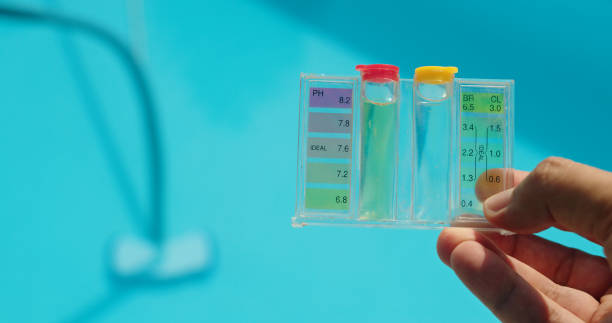 istock A hand holds a water test kit over a bright blue pool, with sunlight reflecting off the water's surface. 2169563750