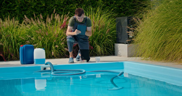istock Pool technician using a tablet by the pool, surrounded by chemical containers and greenery, focused on water quality. 2169563922