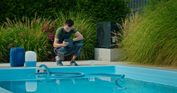 istock Pool maintenance technician using a tablet beside a swimming pool surrounded by ornamental grasses and chemical containers. 2169564597