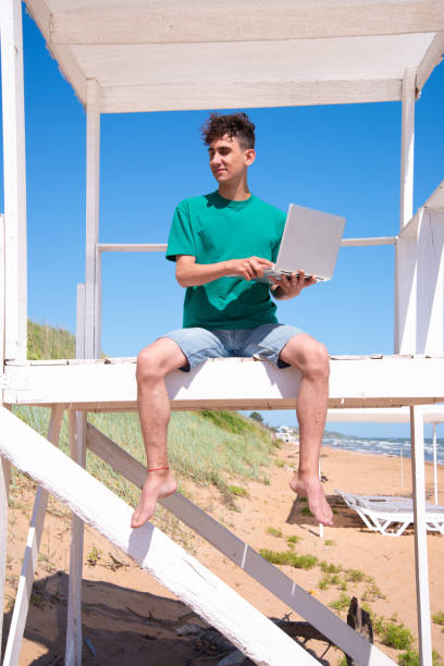 istock A young attractive man relaxes and studies by the sea. 2169564639