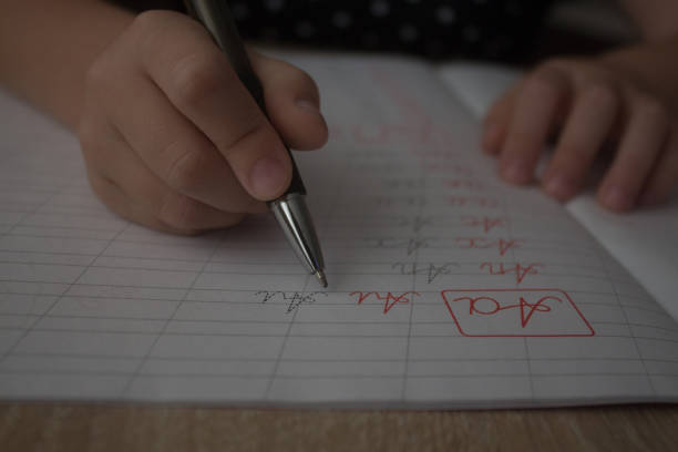 Kid writing nine nine multiplication with pencilon paper. Mathematical.
