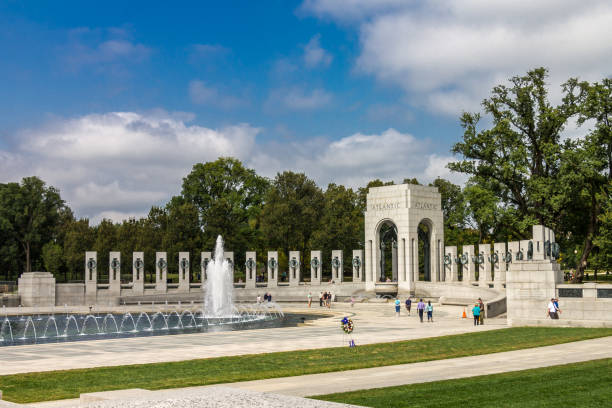 Washington D.C., USA - May 23, 2025. Tourists walk around the World War II Memorial with fountains spraying water into the air.