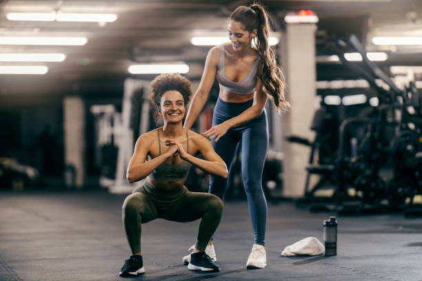istock Happy sportswoman doing squats endurance while her coach is helping her. 2169583573