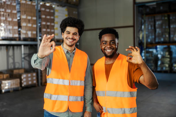 istock Cheerful diverse warehouse staff standing in facility and gesturing okay. 2169584390
