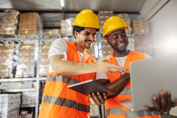 istock Smiling multiracial warehouse specialists standing in facility and using laptop and tablet for automation. 2169584993