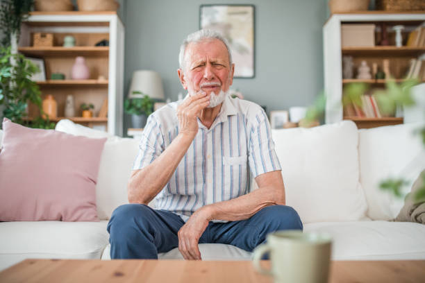 istock A senior man has a severe toothache while sitting in the living room 2169601975