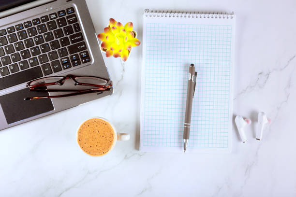 istock Desk is equipped with laptop, coffee cup, pen, a notebook on top 2169603794
