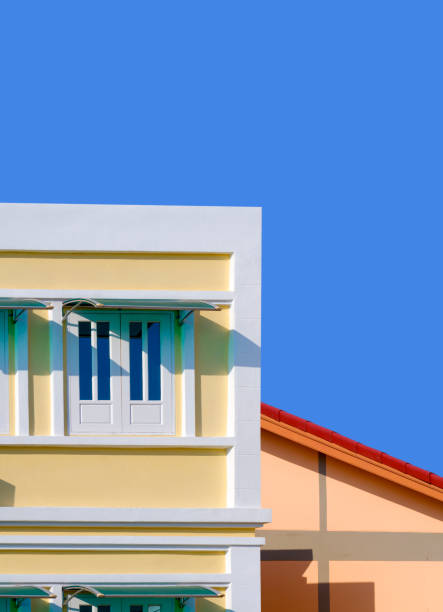Modern house building with glass window and line pattern on colorful concrete wall against blue sky background in minimal style and vertical frame