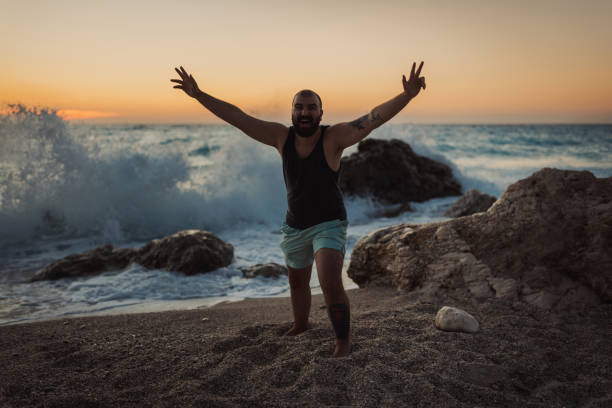 Portrait of a happy young bearded man having fun at the beach on a sunny summer day during a vacation at the seaside