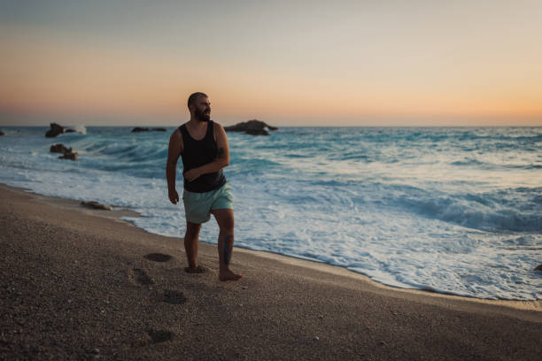 Happy young bearded man enjoying a vacation at the seaside and walking at the beach on a lovely summer day