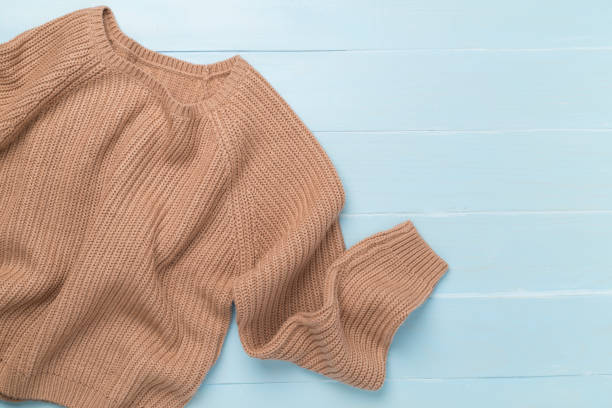 istock Brown sweater on wooden background, top view 2169624715