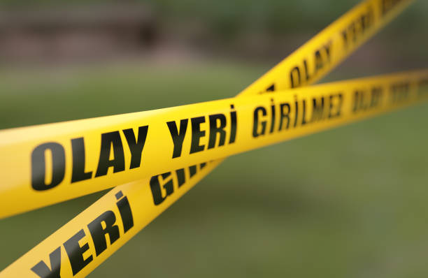 Yellow crime scene do not cross barrier tape in front of defocused background. Horizontal composition with selective focus and copy space.