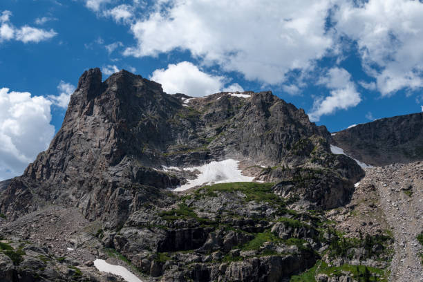 istock Majestic mountain peak under a bright blue sky with scattered clouds in summer, showcasing rocky terrain and patches of snow 2169634765